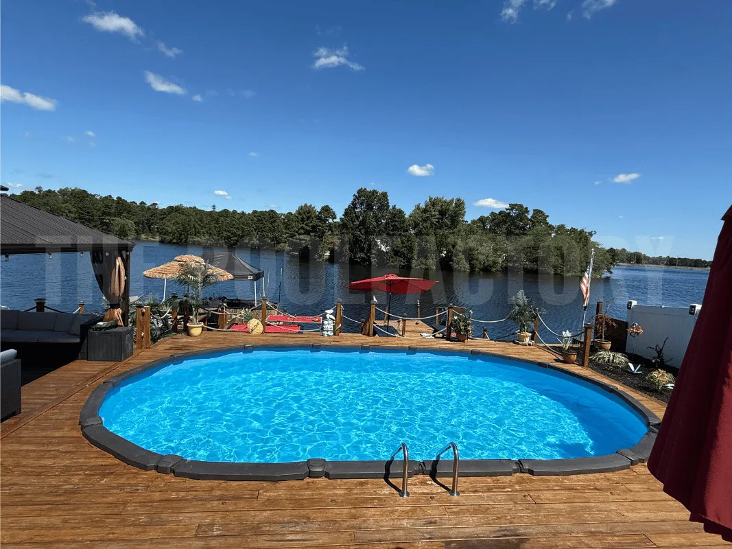 Semi-inground oval saltwater pool featuring wraparound deck and vibrant sunset view over the water