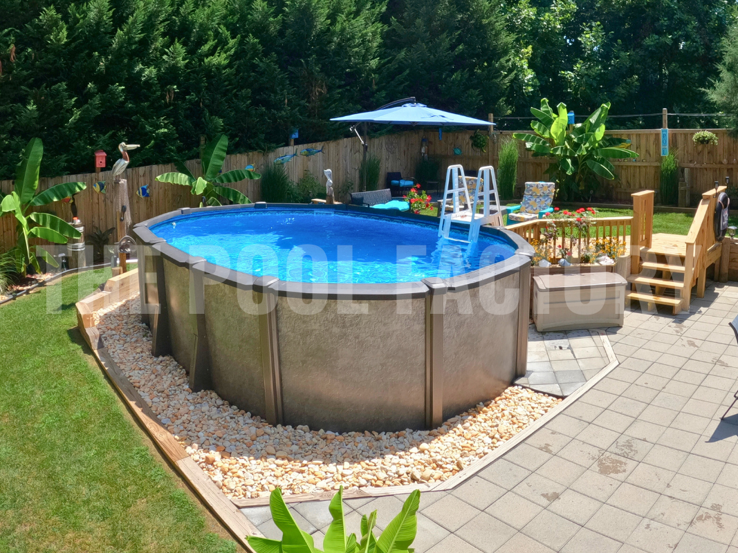 Above ground oval pool with decorative rocks, landscaping, stone patio, and flowers