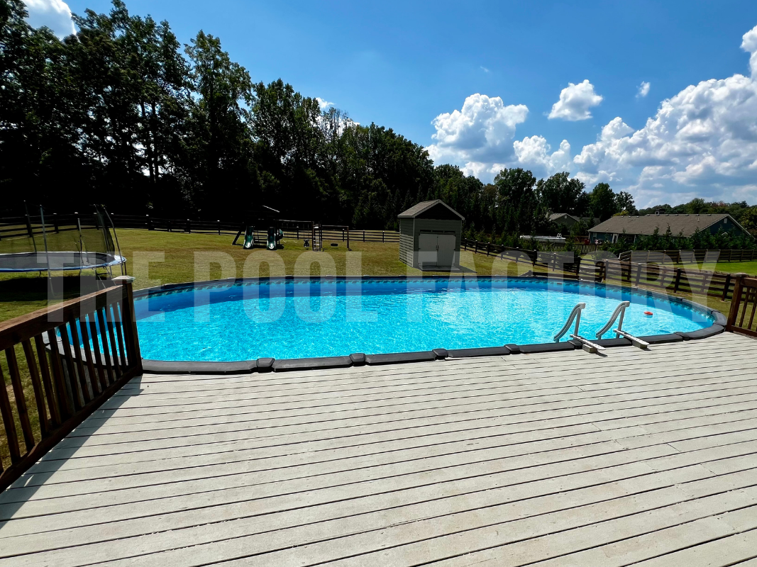 Oval saltwater swimming pool with partial deck and forest landscape