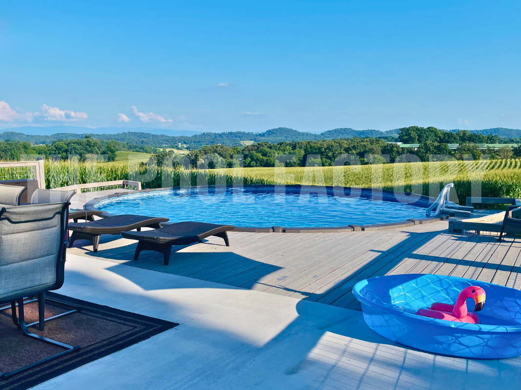 Above ground round swimming pool with partial deck and lounge chairs on a clear sunny day