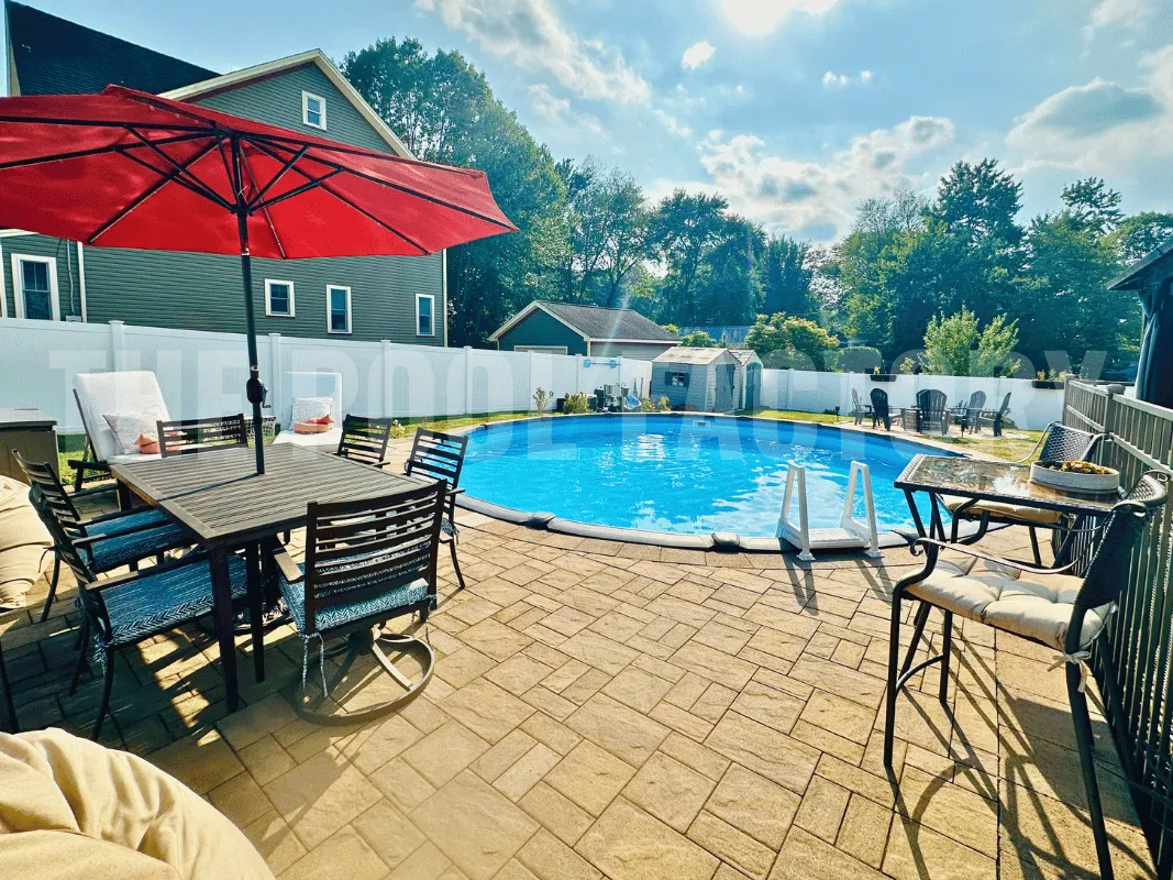 Round pool surrounded by outdoor patio with natural stone flooring and backyard furniture set