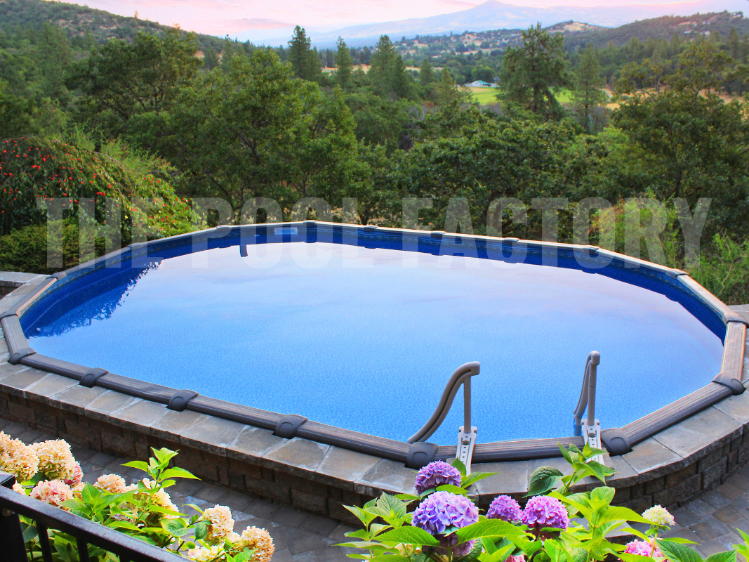 Above ground oval pool with forest view, stone deck, and surrounded by flowering plants 