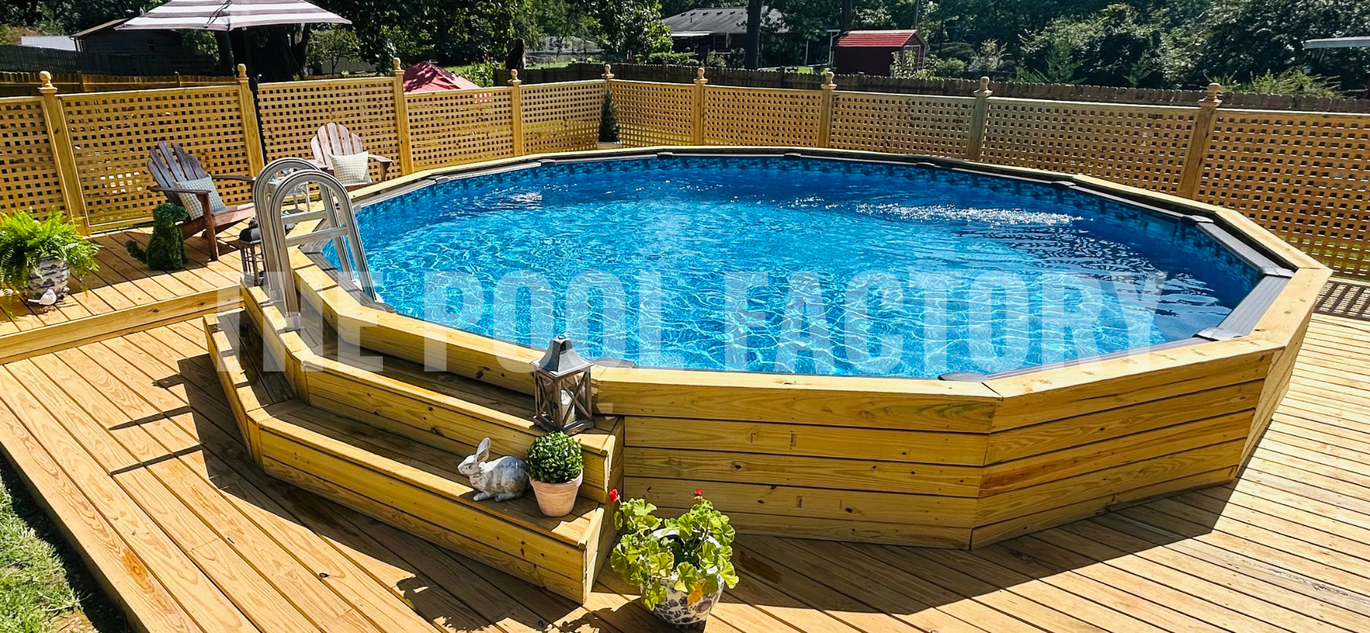 Round swimming pool with full wrap around deck with steps on a sunny day