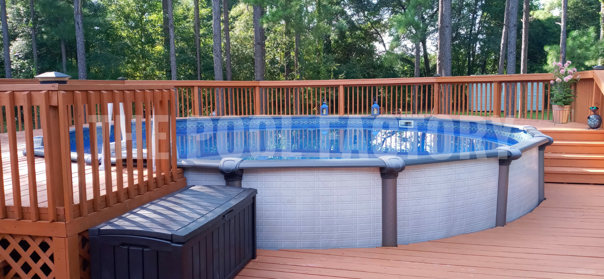 Round swimming pool with steps leading to a full deck, surrounded by trees