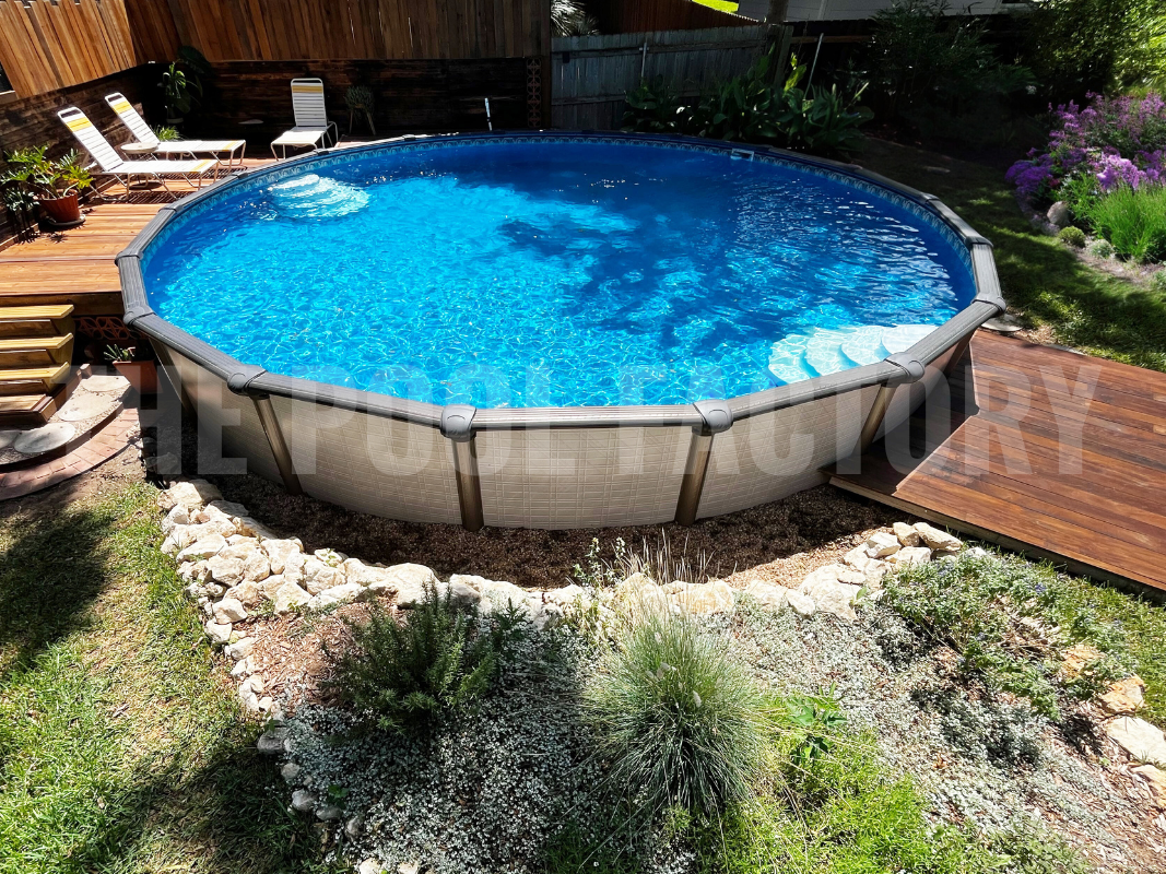 Round semi-inground pool surrounded by flowers and decorative rocks