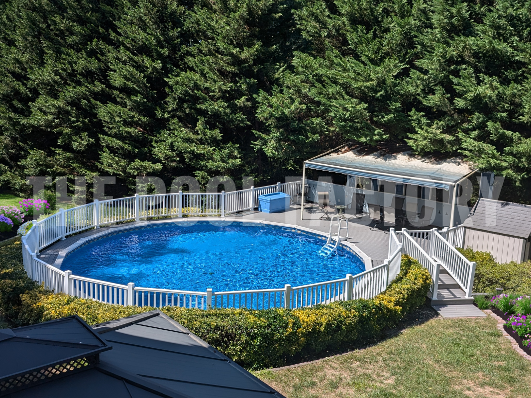 Round semi-ground pool with a deck and flower garden on a sunny day