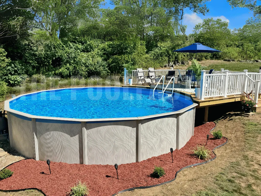 Round above ground pool with partial wooden deck, mulch border, and vibrant backyard flowers