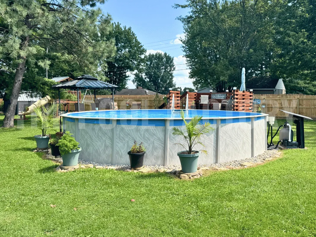 Round pool surrounded by mulch, flower pots, and trimmed lawn