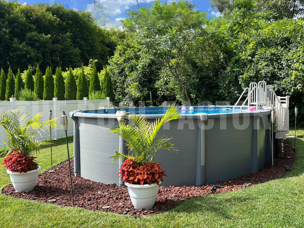 Above ground oval swimming pool with mulch, plants and privacy vinyl fence