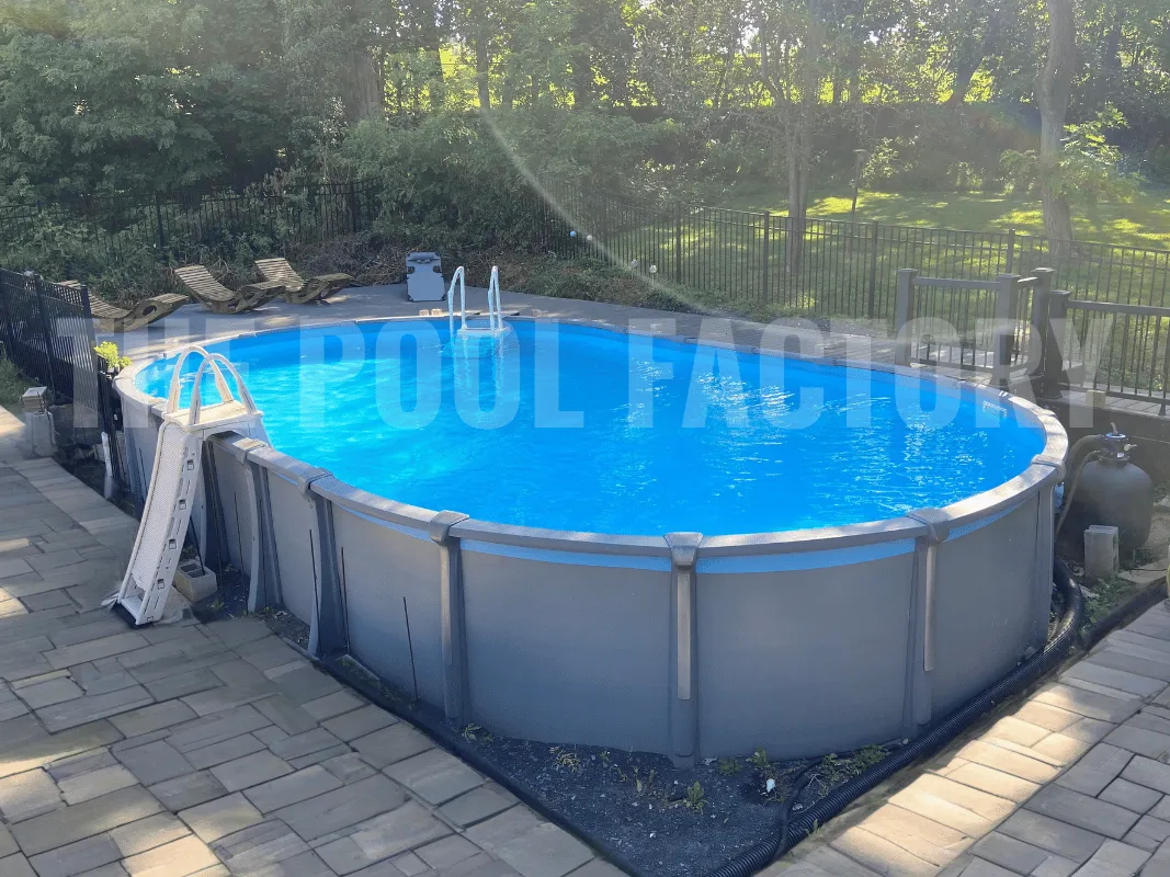 Above ground oval pool with stone border, a-frame ladder, and beautiful tree-lined yard