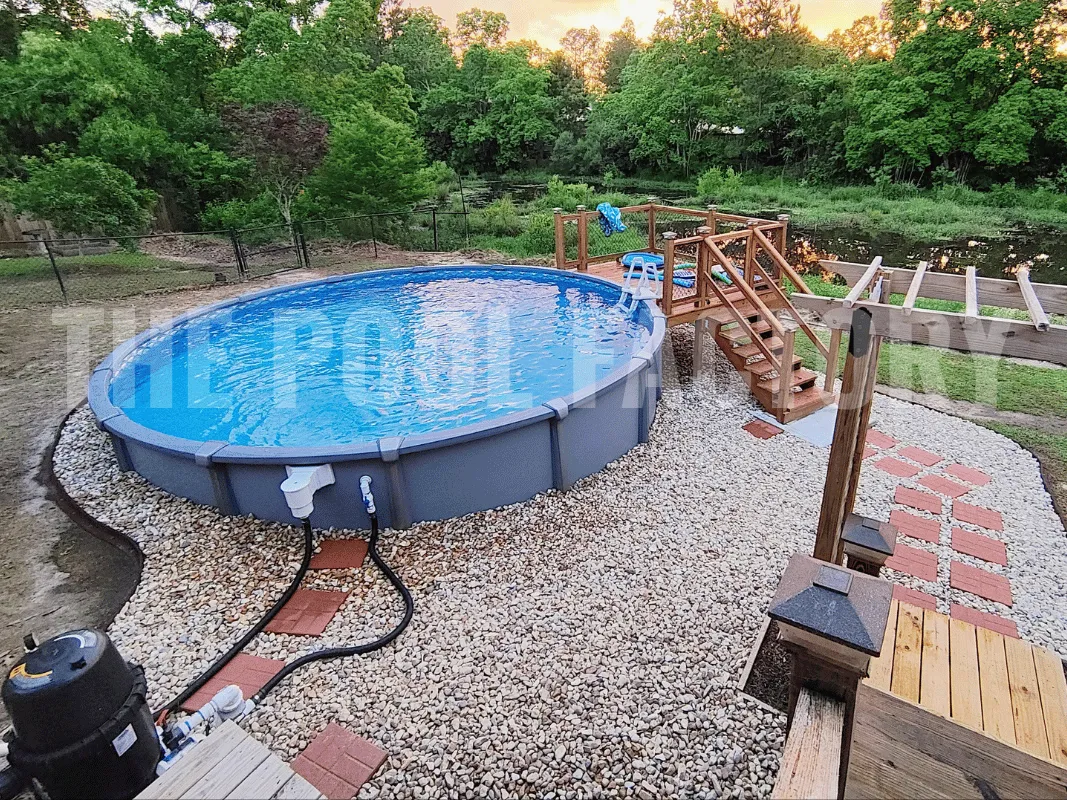 Fully resin semi-inground swimming pool surrounded by a partial deck and decorative rock