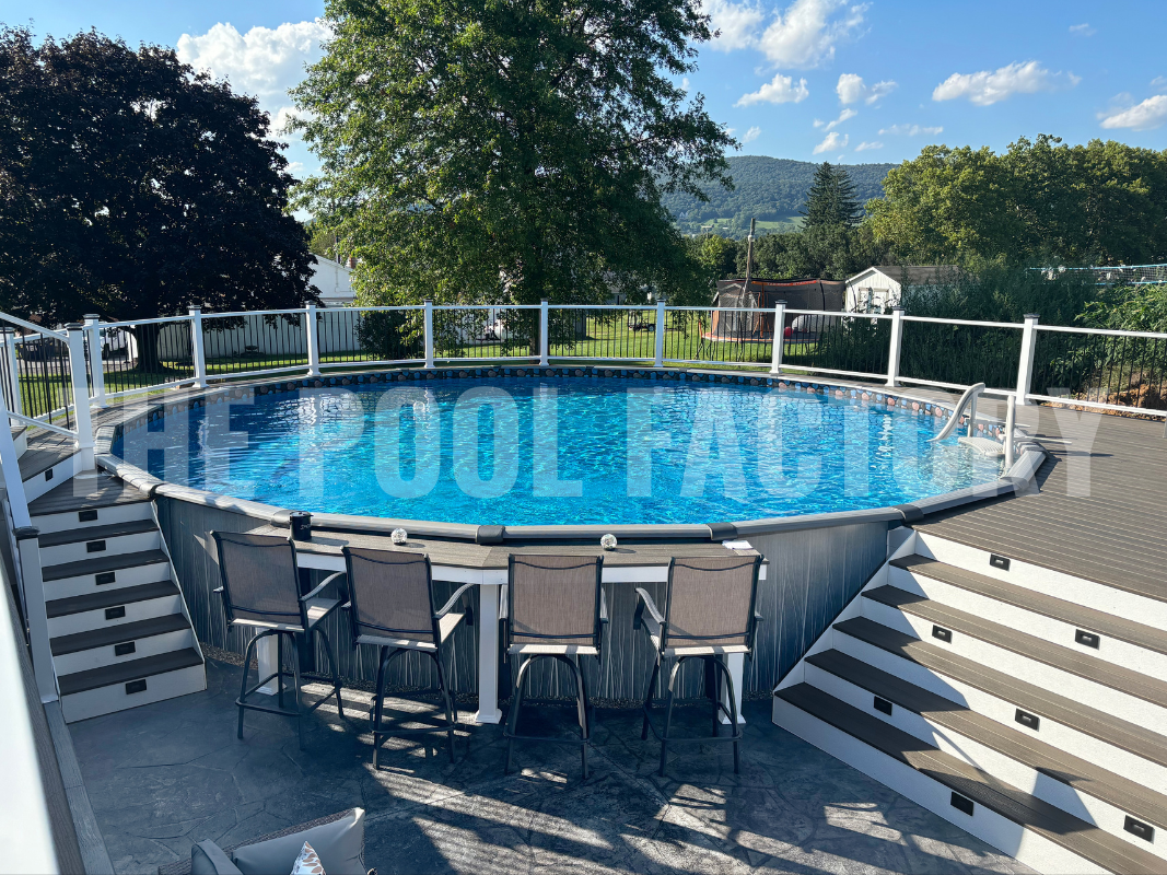 Round above ground swimming pool surrounded by a large deck with bar seating and a forest view