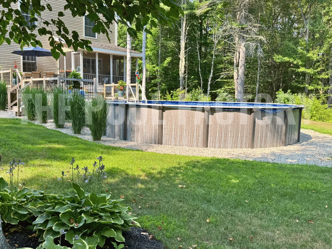 Backyard round above ground pool surrounded by mulch, hedges, and tall greenery