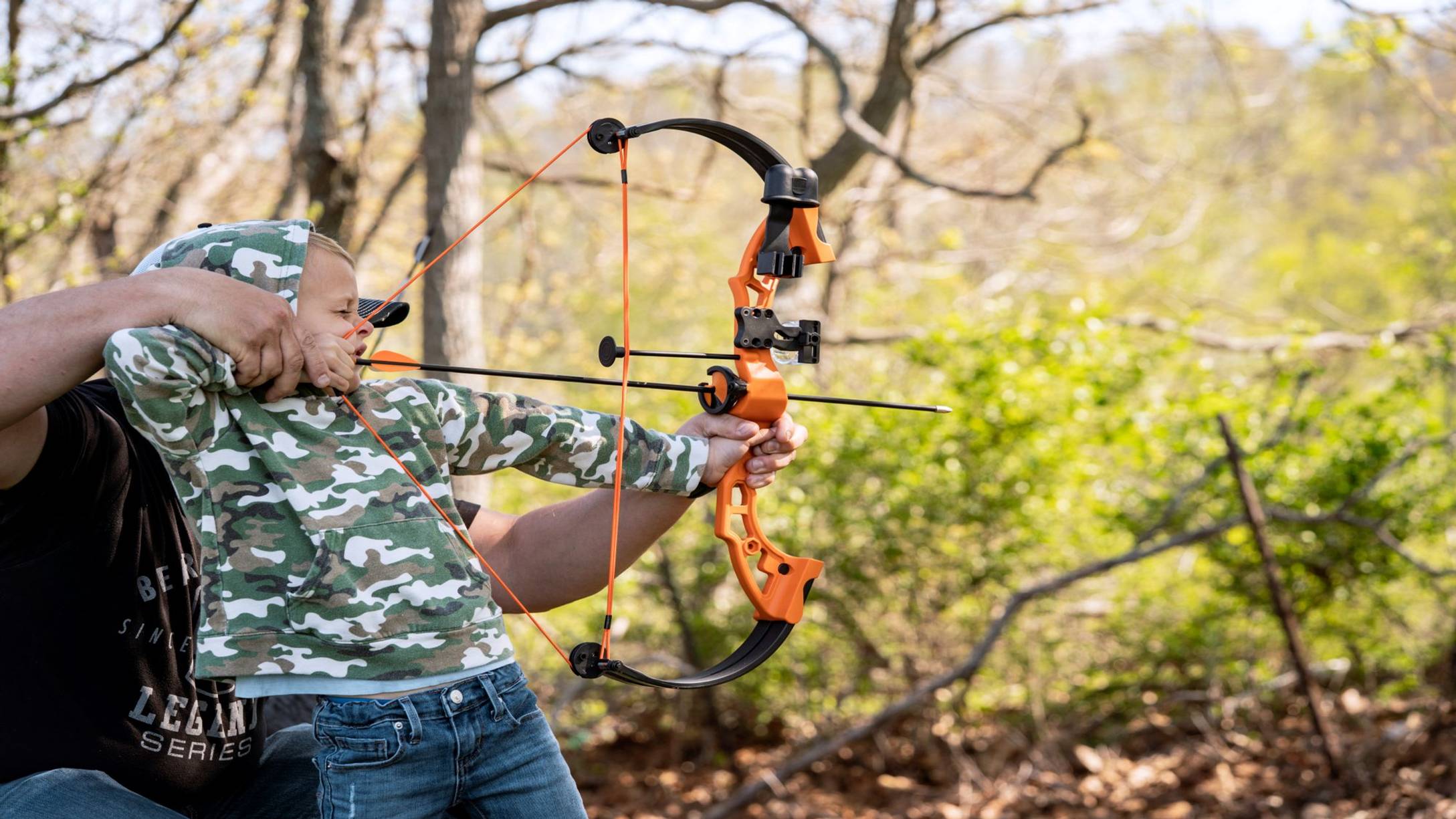 Child shooting the Brave youth archery bow from Bear Archery with help from an adult.