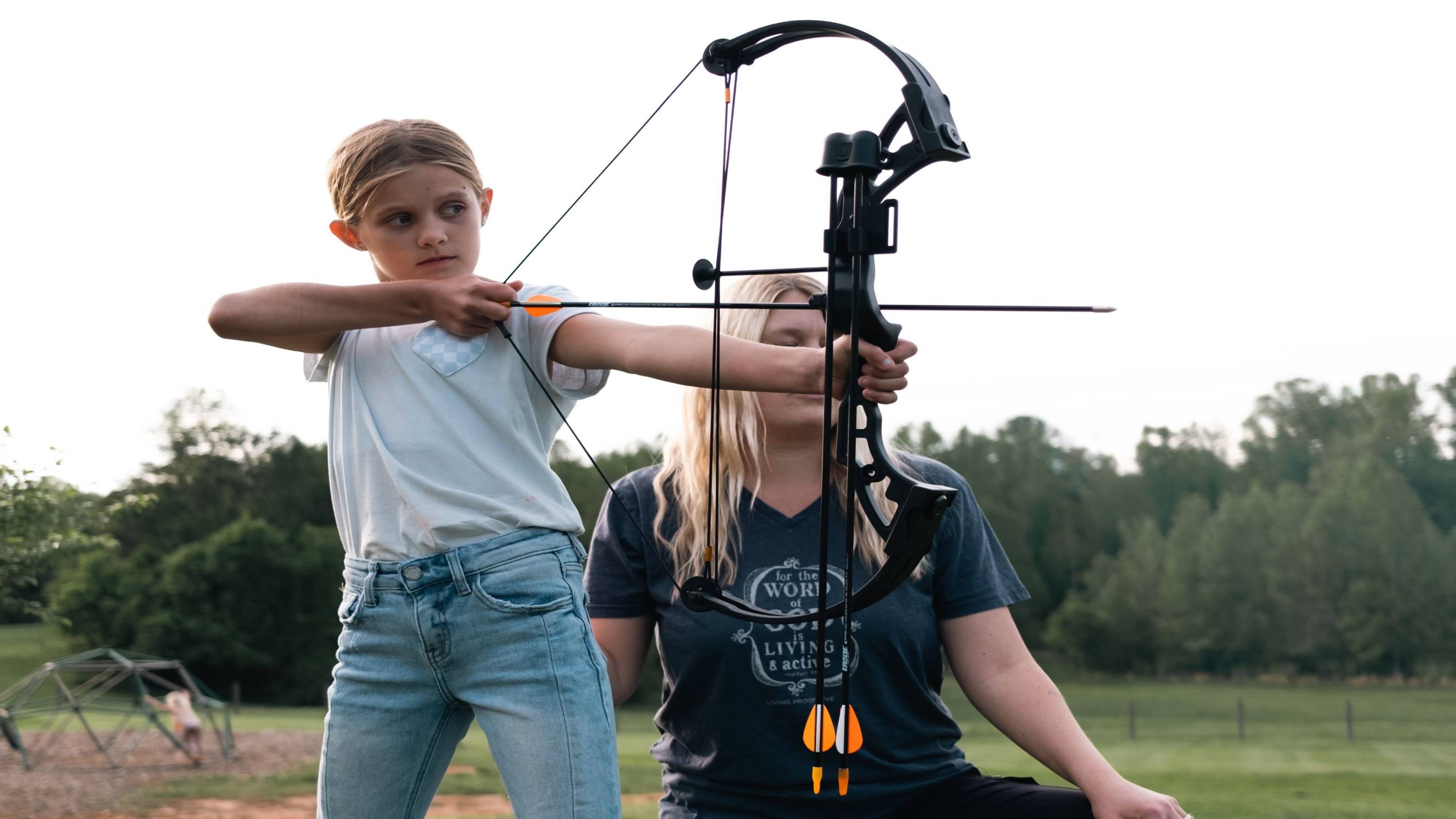 A mother teaching her daughter how to shoot the Brave youth bow from Bear Archery