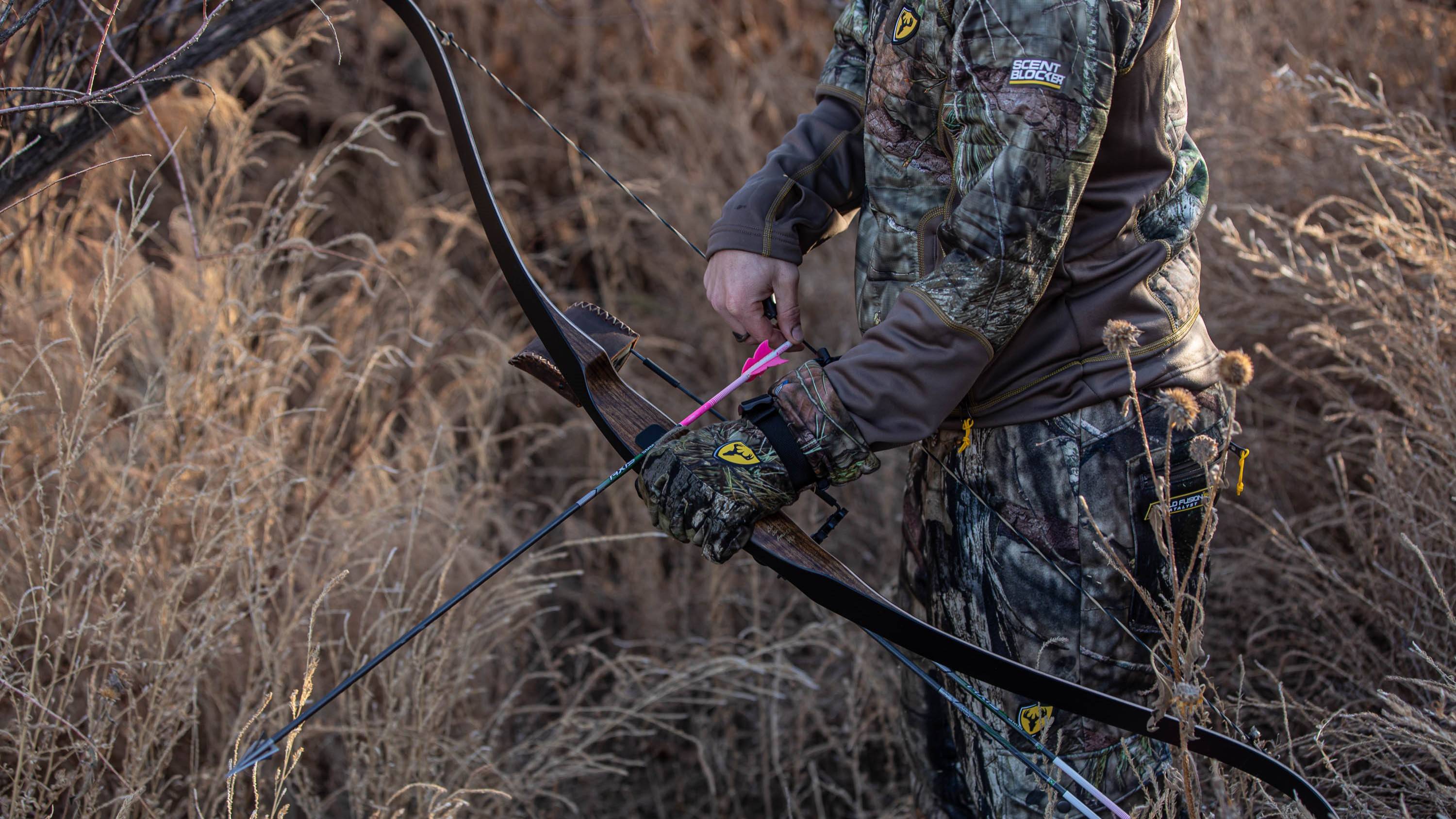 Man holding a Bear Archery Grizzly Recurve Bow with an arrow nocked