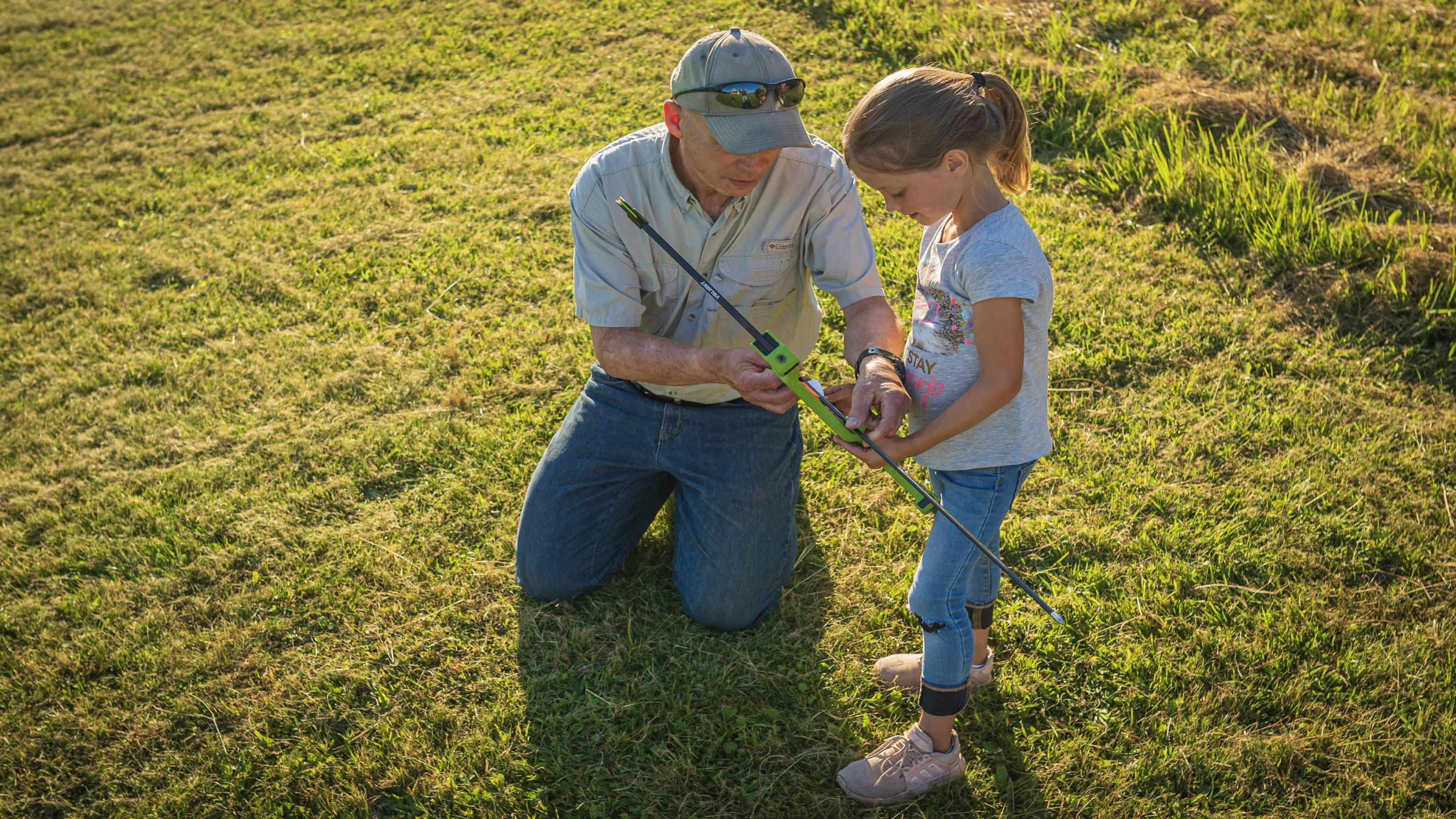 Grandfather showing granddaughter how to shoot a bow with the Valiant youth bow from Bear Archery