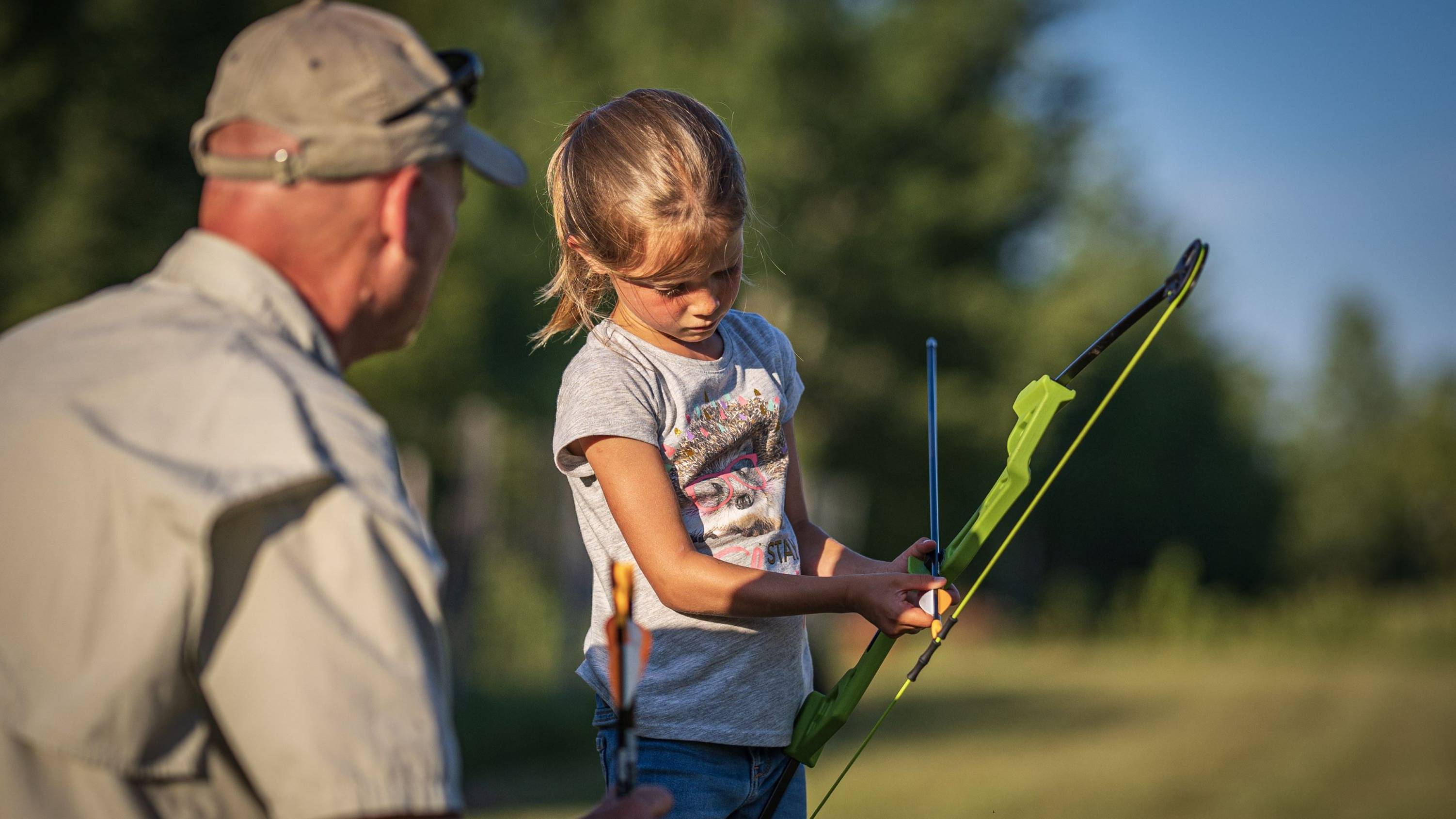 Grandpa helping granddaughter shoot the Valiant youth bow from Bear Archery