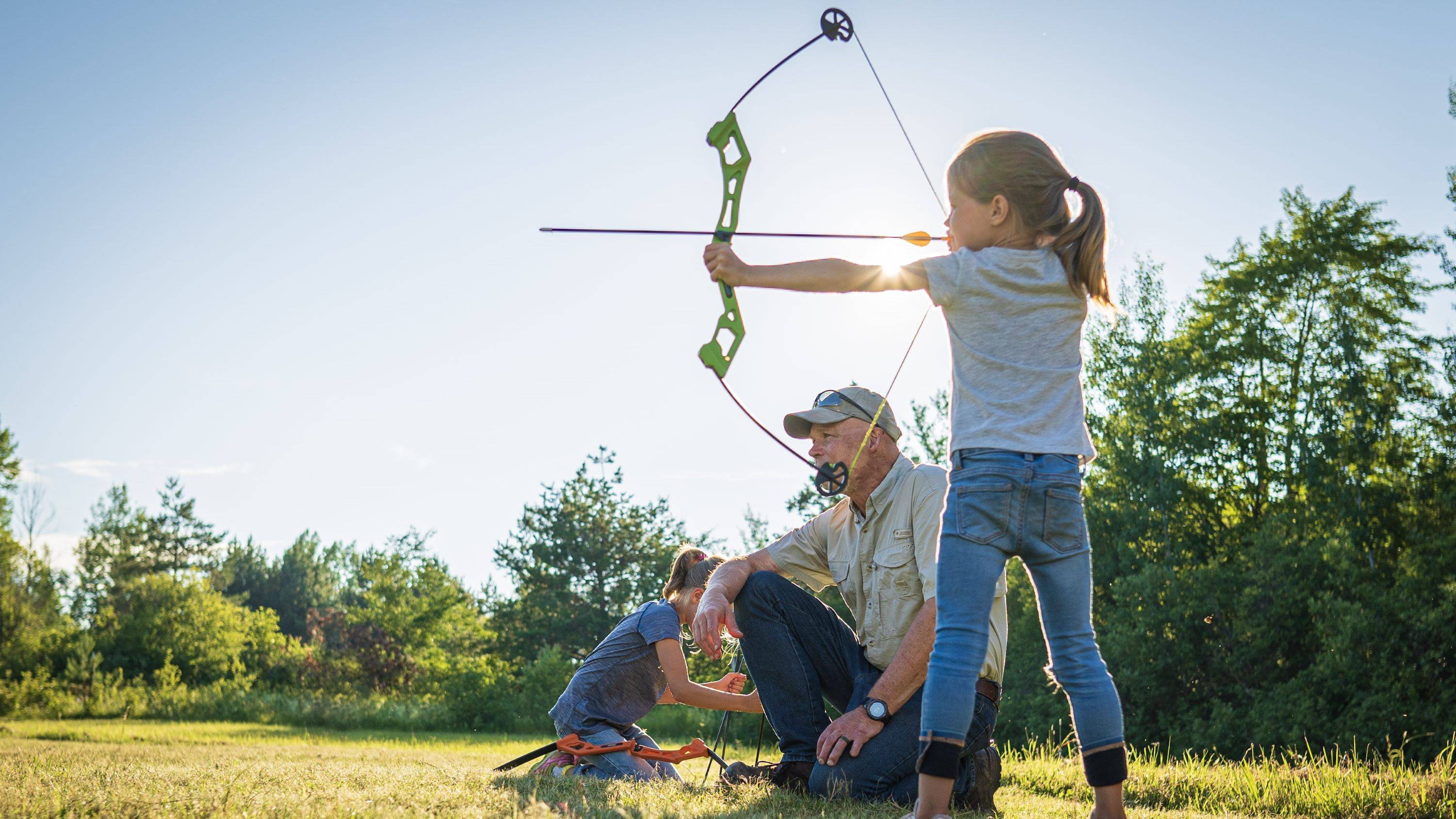 Girl shooting the Bear Archery Valiant youth bow while her grandpa helps