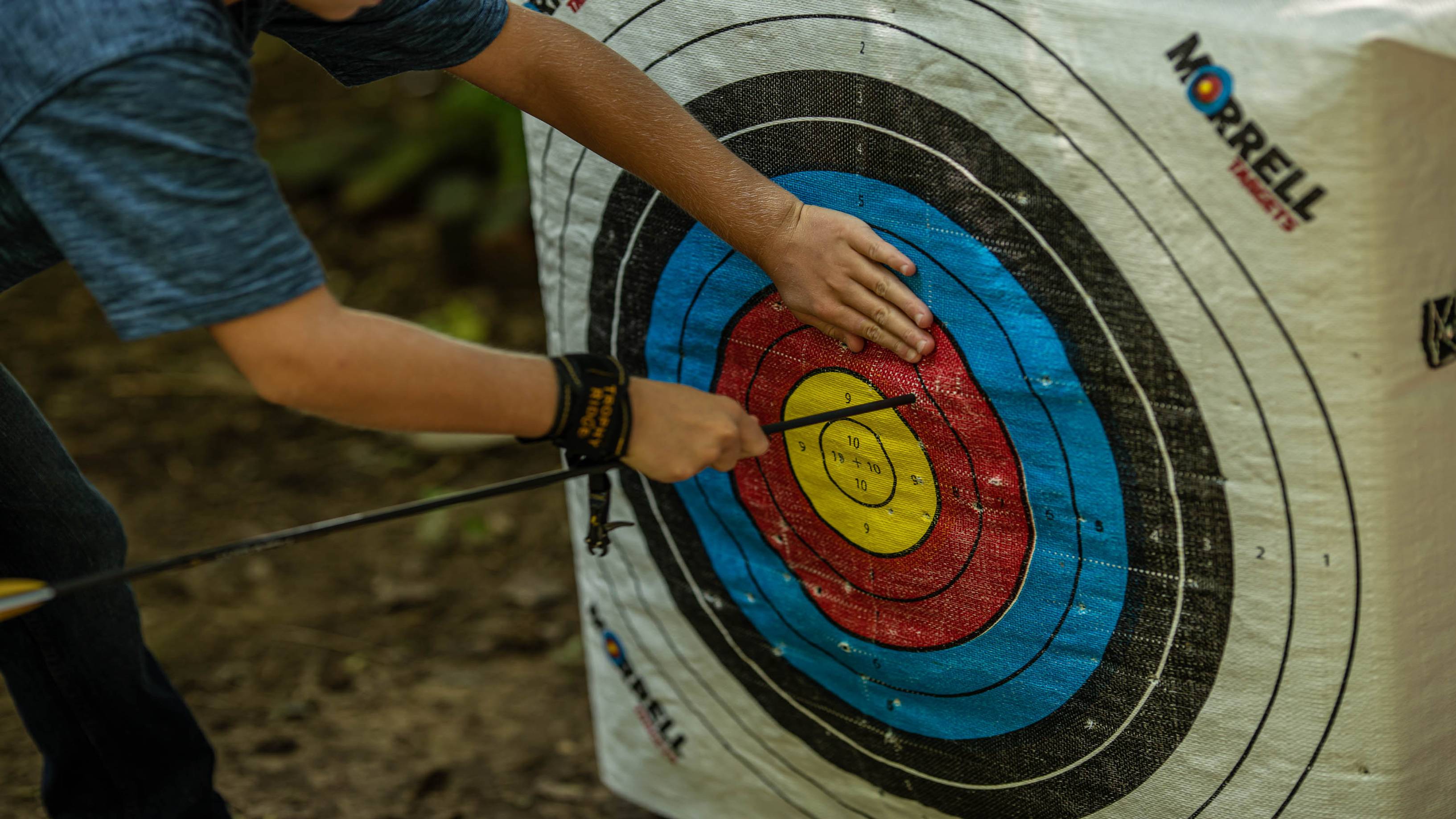 Kid pulling an arrow out of a target with the ArchX Youth wrist strap release from Trophy Ridge on his wrist