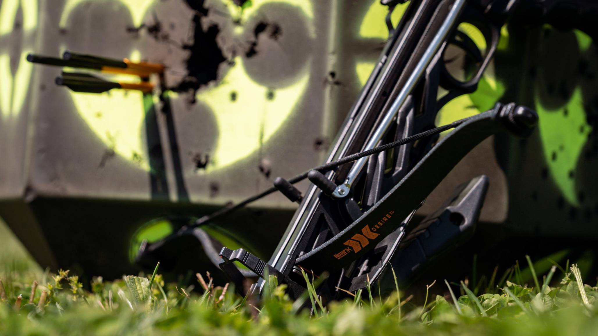 Close up of the Bear X Desire XL pistol crossbow leaning in front of crossbow bolts