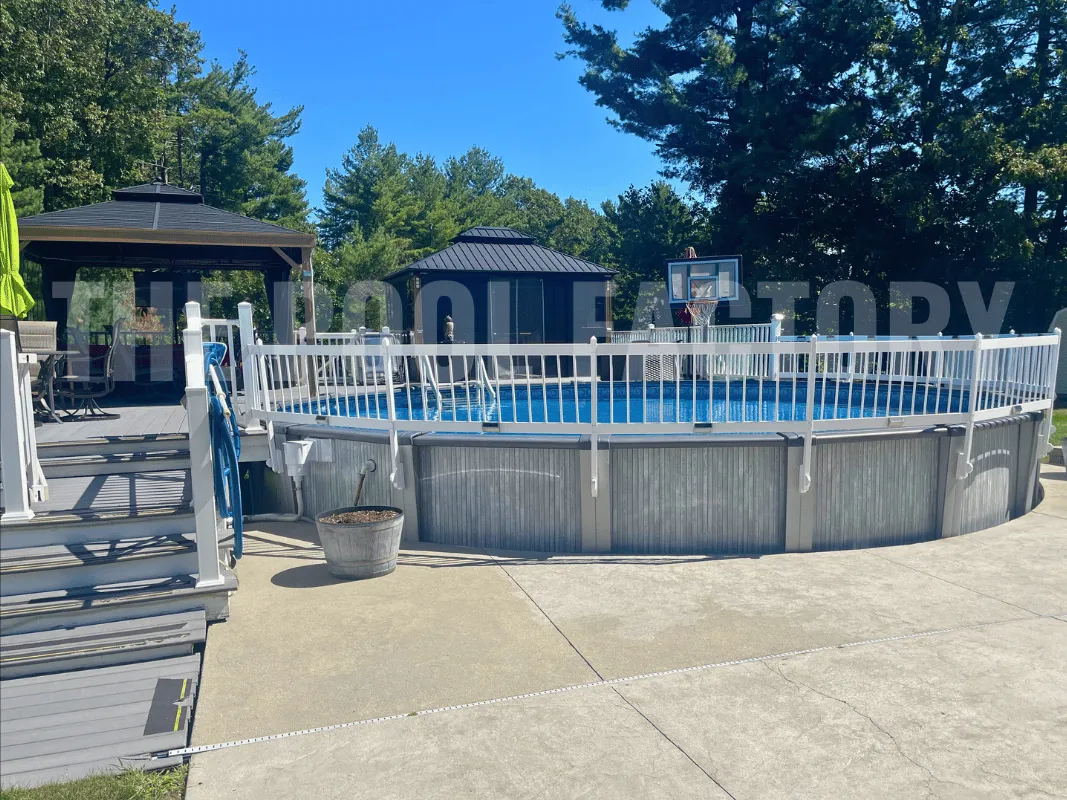 Round above ground pool enclosed by safety fence and partial deck