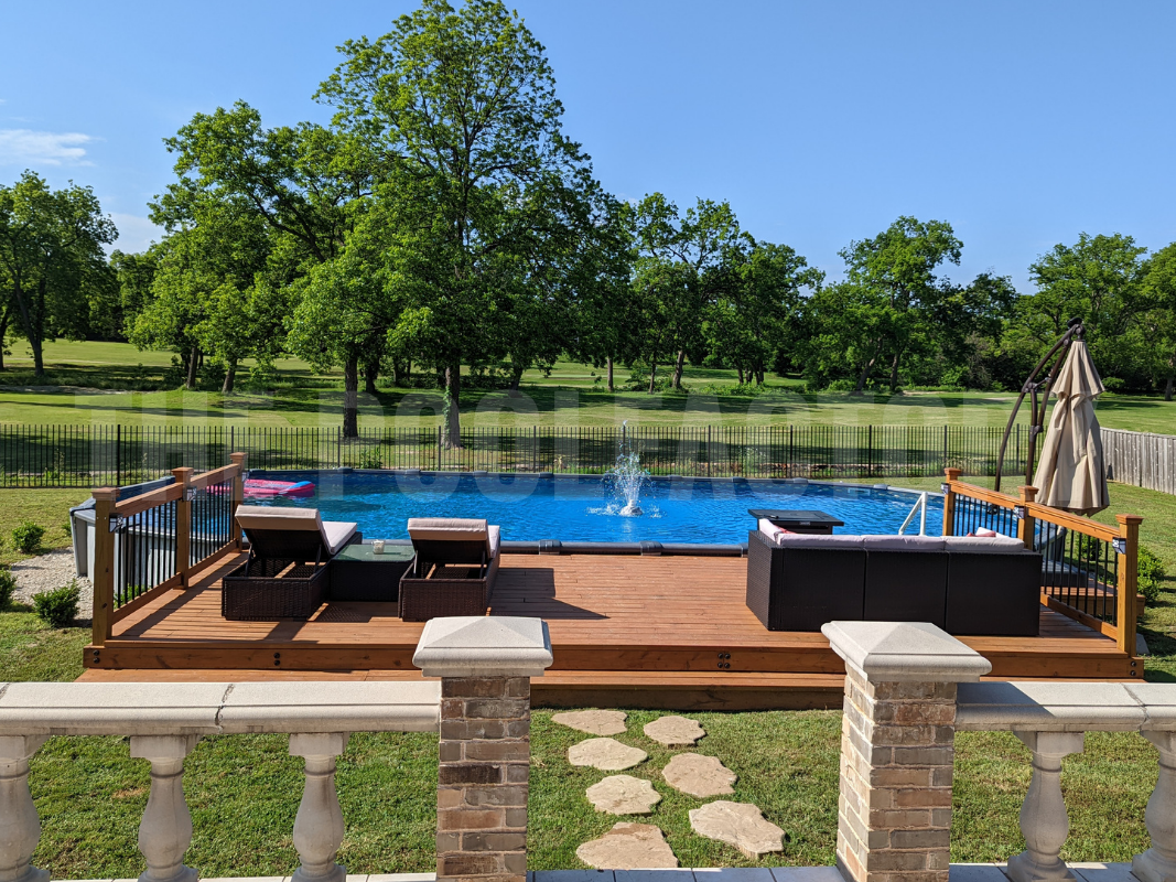 Above ground oval pool with surrounding trees and partial wooden deck