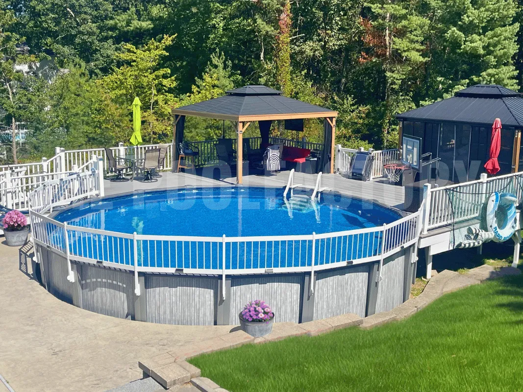 Round above ground pool with safety fence and a wooden pergola providing shade beside a landscaped garden and green lawn