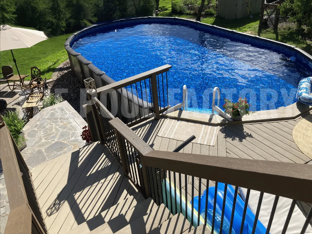 Oval above ground pool with expansive deck, outdoor lounge seating, and sunny open backyard