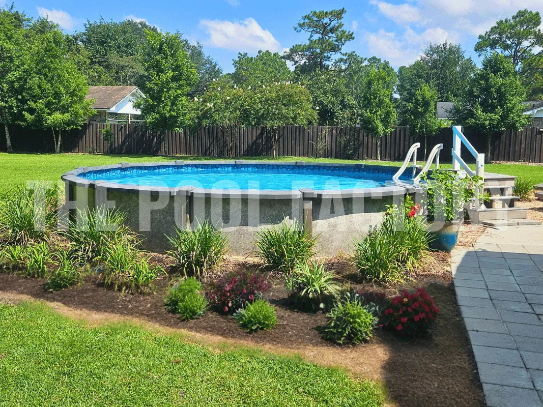 Round semi-inground pool surrounded by vibrant green lawn and garden flowers on a sunny day