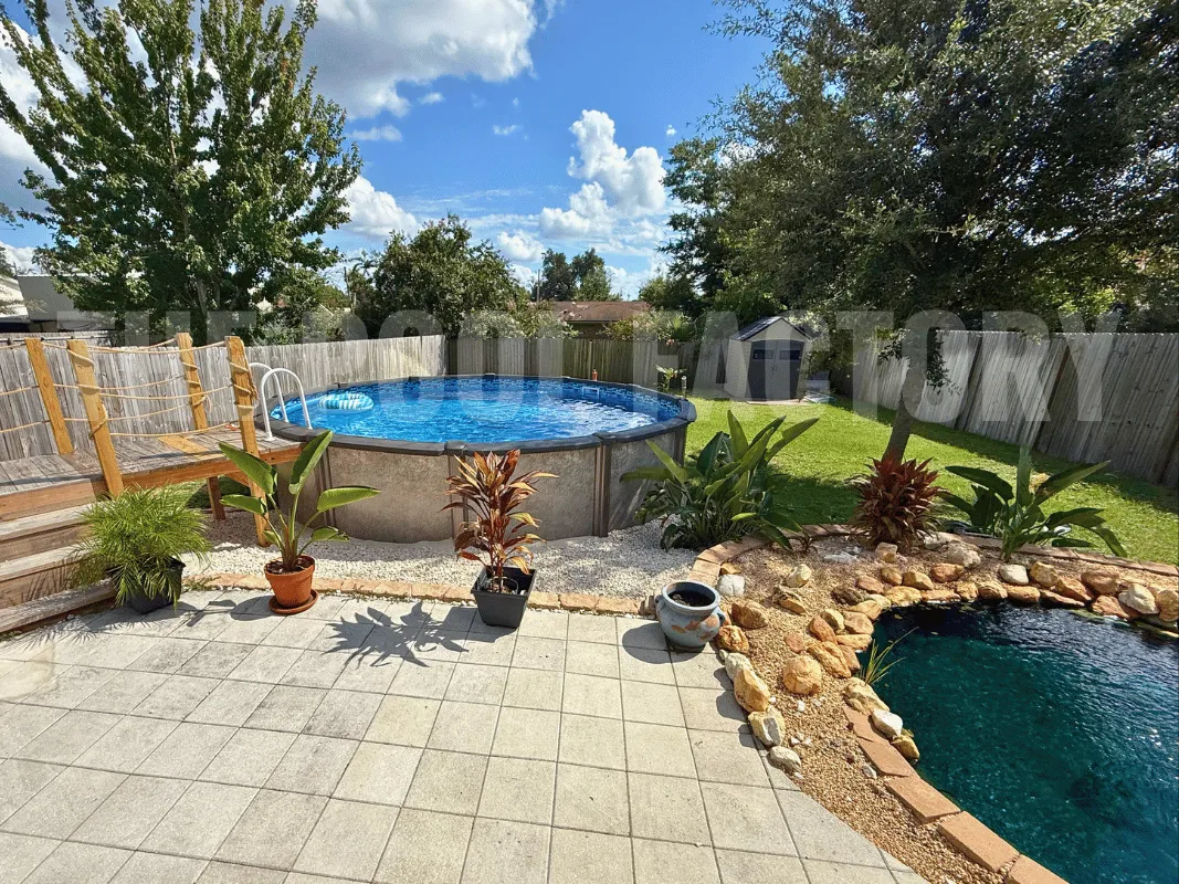 Round pool with small pond nearby, stone landscaping, and bright summer sunlight