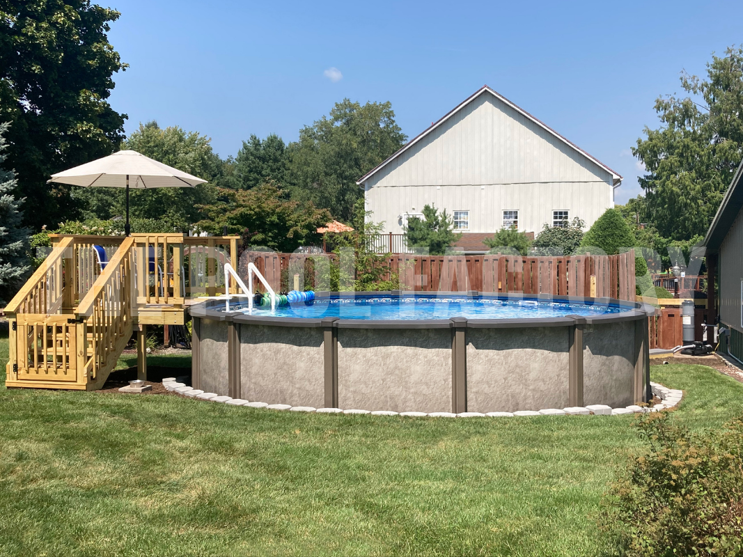 Above ground round swimming pool with partial deck and a well maintained lawn