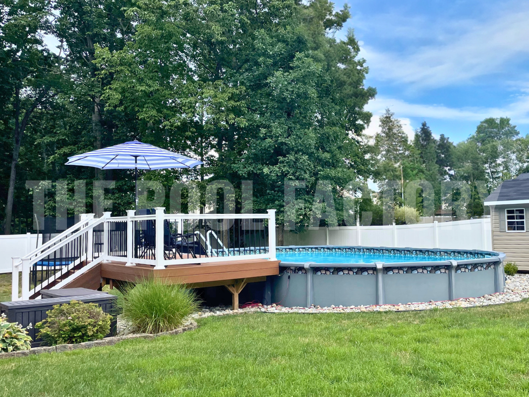 Semi-inground oval saltwater pool with partial deck and decorative rocks surrounding