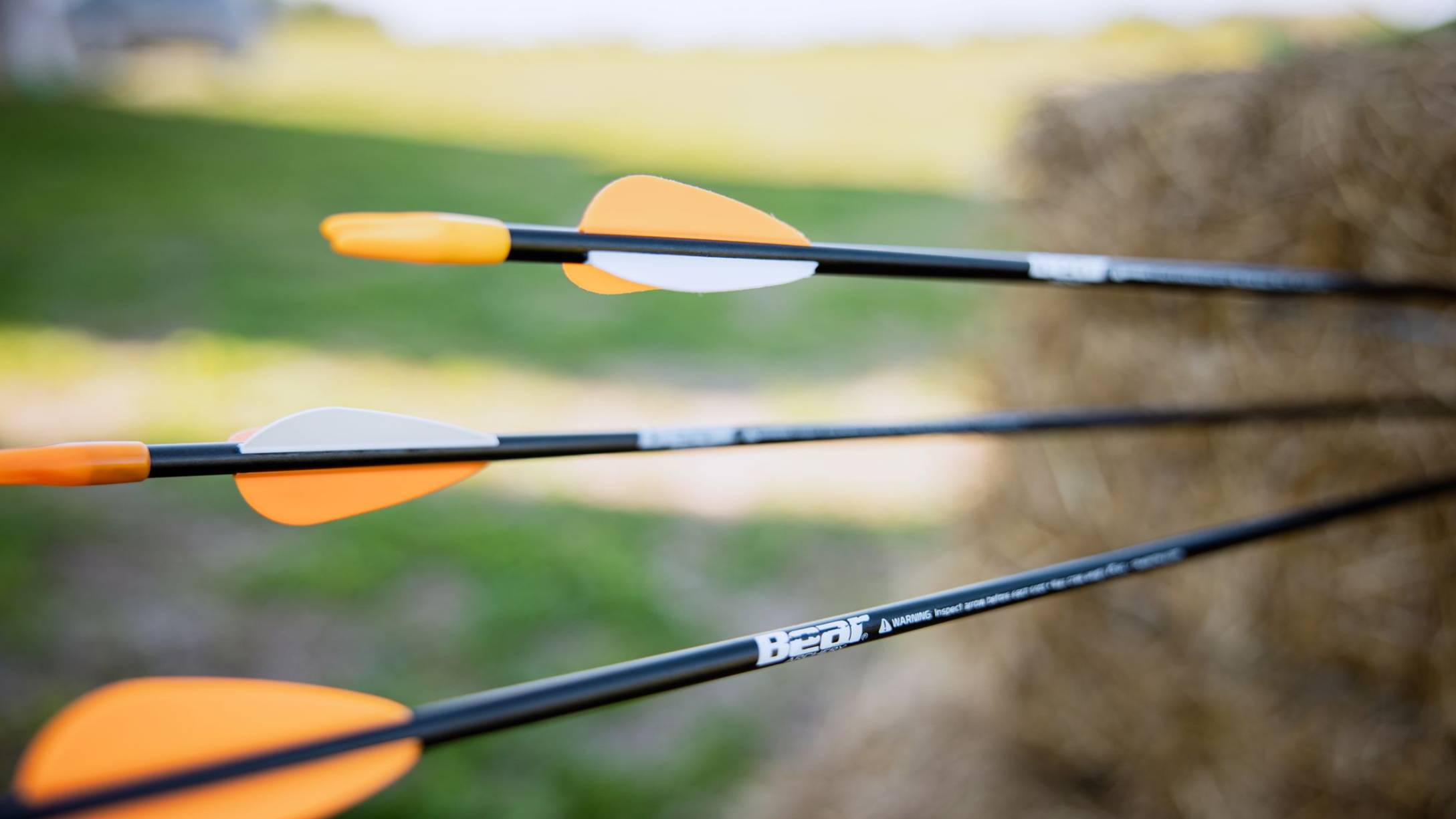 Close up of Youth Safetyglass Arrows from Bear Archery stuck in a hay bail. 