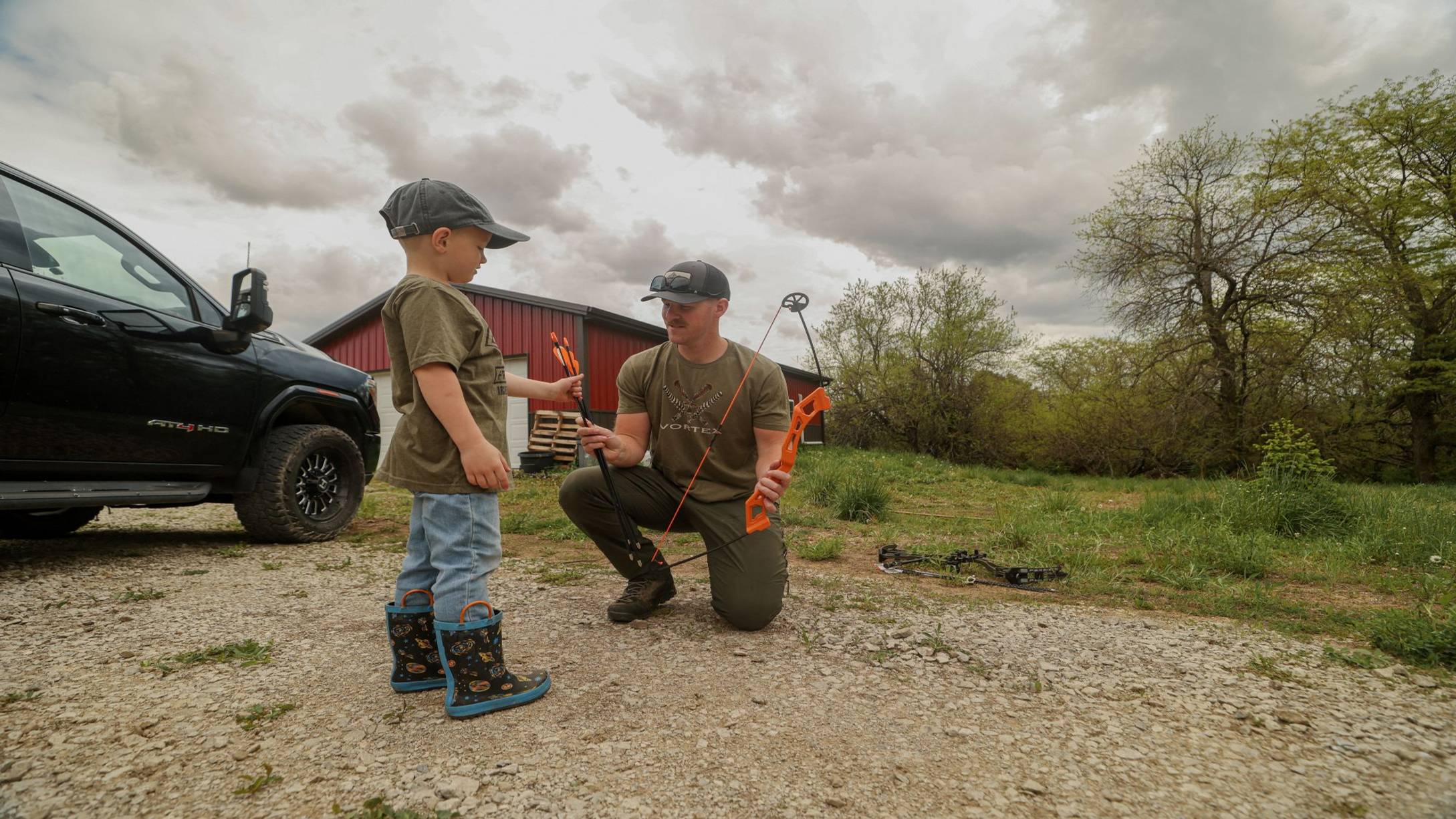 Boy taking Bear Archery Youth Safetyglass Arrows from his father. 