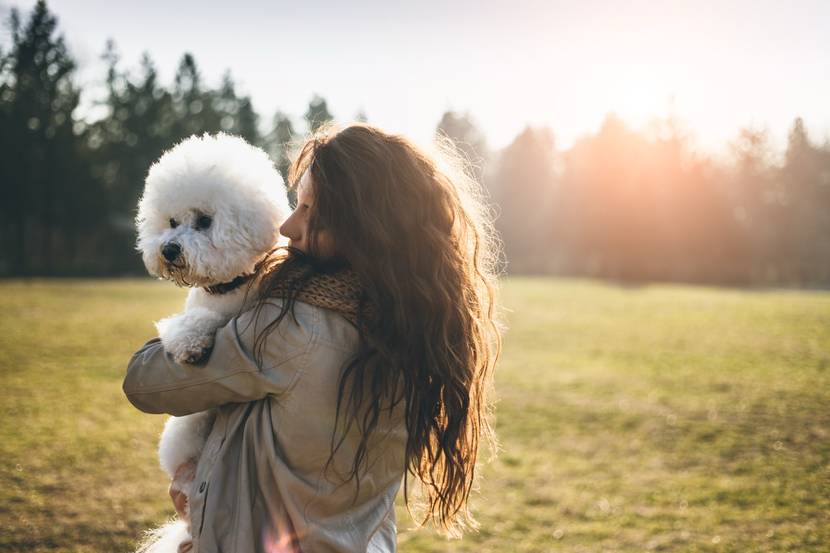 Frau trägt Hund auf Arm