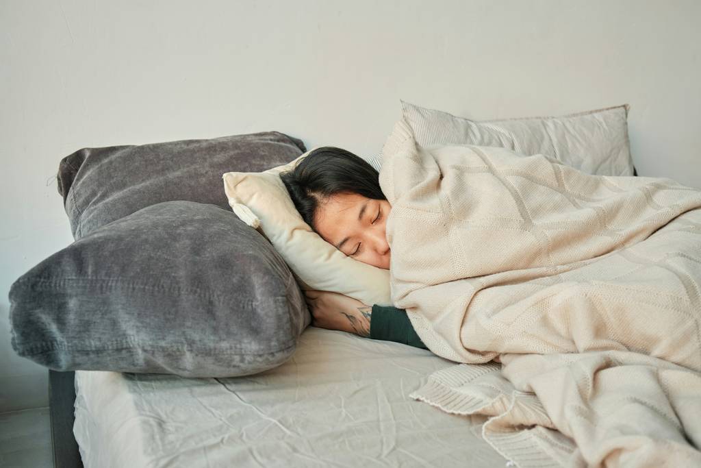 woman sleeping on bed with grey pillow and beige minky couture blanket