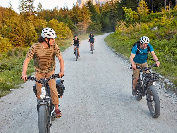 Family of four riding their RadRover 6 Plus ebikes on a gravel road.