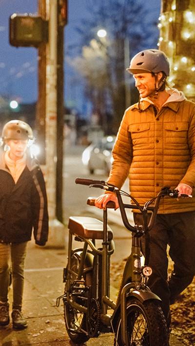 Man with a RadRunner 2 electric cargo bike walking with a young boy