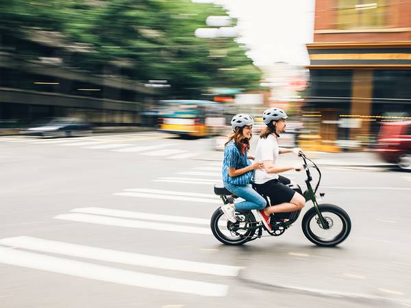 A couple riding a RadRunner 2 ebike together turn a corner
