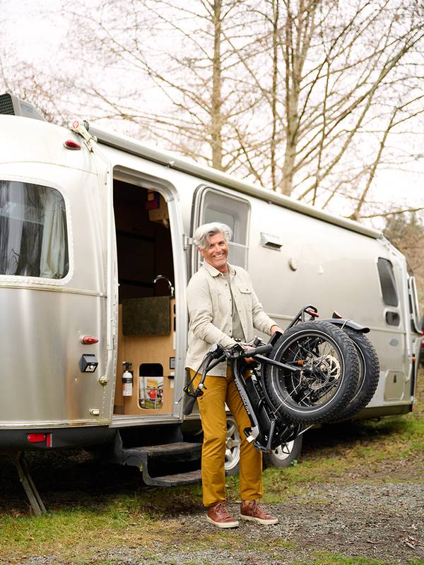 A man carries a folded RadExpand ebike out of a trailer