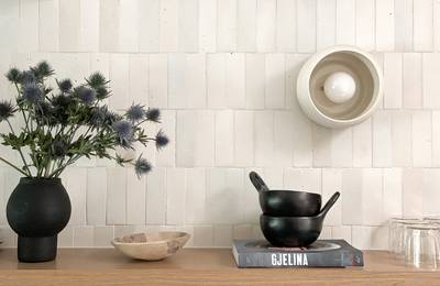  clé tile terracotta mochi white 2x6 tiles installed on a kitchen wall with open shelving and flowers