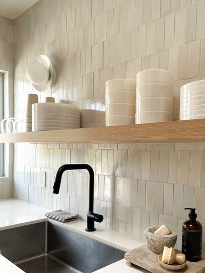 clé tile terracotta mochi white 2x6 tiles installed on a kitchen wall and backsplash with open shelving over a sink.

