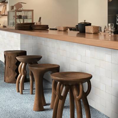  clé tile terracotta mochi white tiles installed on the bar front of a restaurant with carved wooden stools in front