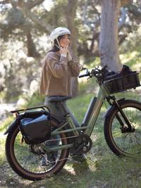 Woman standing next to a Radster Trail electric off-road bike in a grassy area