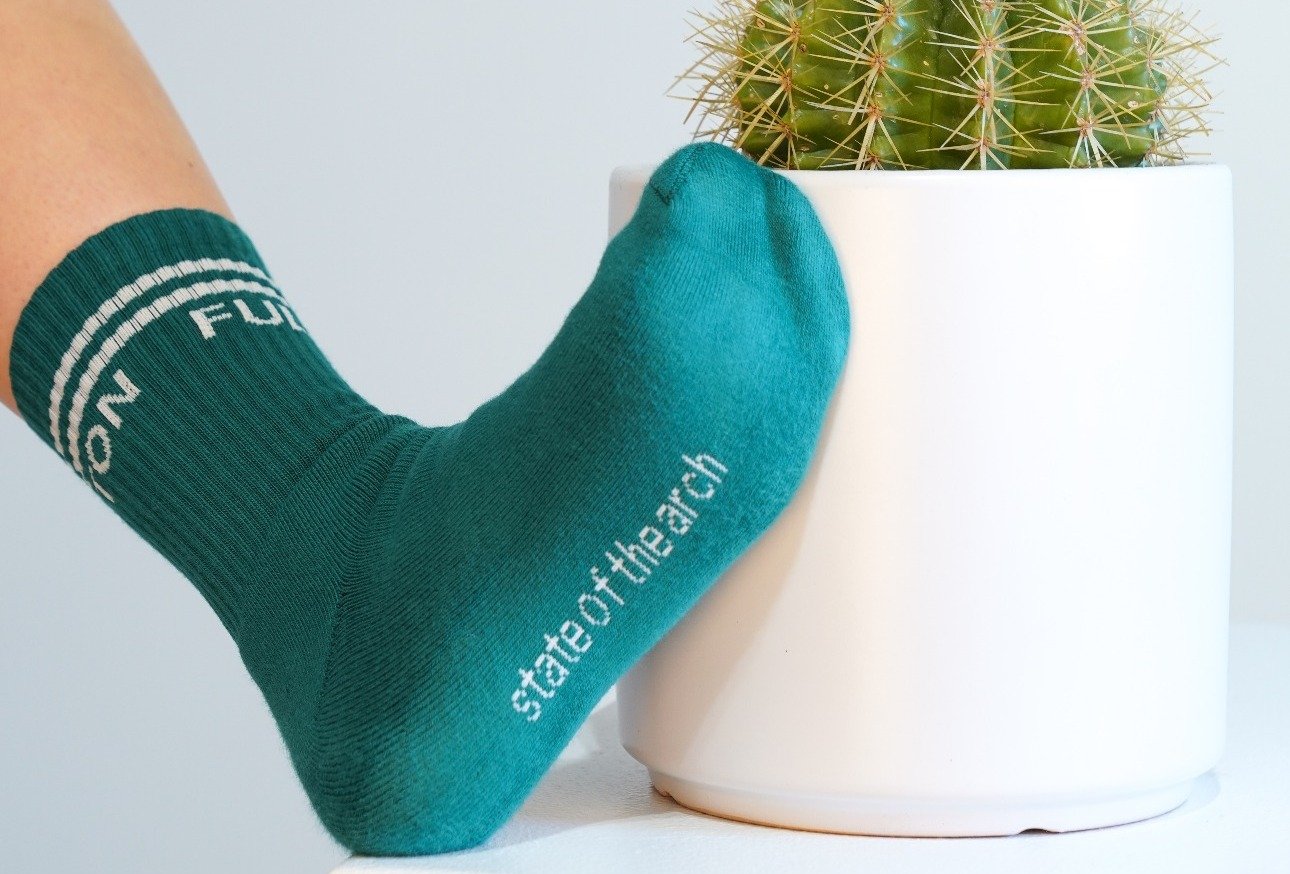 foot in green sock that says state of the arch