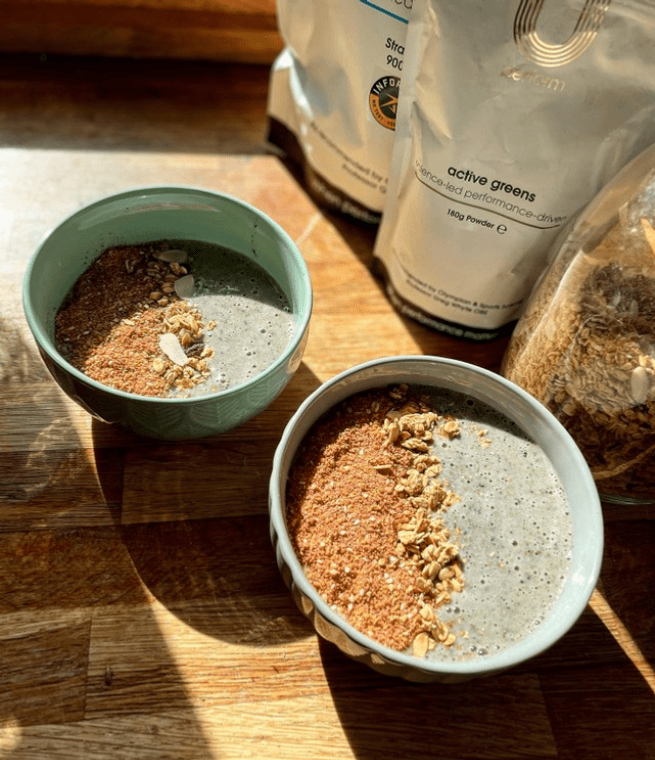 U Perform Active Greens Smoothie Bowls on wooden worktop next to product packaging and a glass jar filled with oats