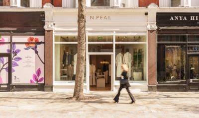 N.Peal Sloane Street storefront with a white facade and large display windows, situated between neighbouring shops, as a person walks past on the pavement