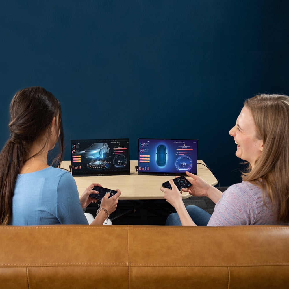 SideTrak Solo Touch Pro HD Triple two women sitting on a couch having fun and laughing while using screens with a gaming system