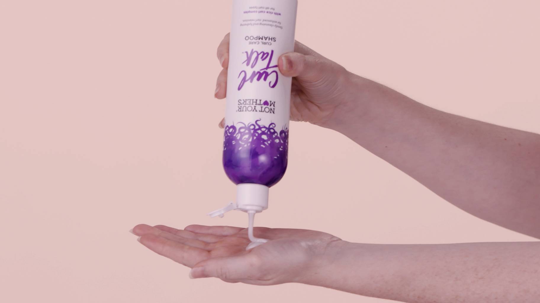 An individual squeezing NYM Curl Talk shampoo into their hand.